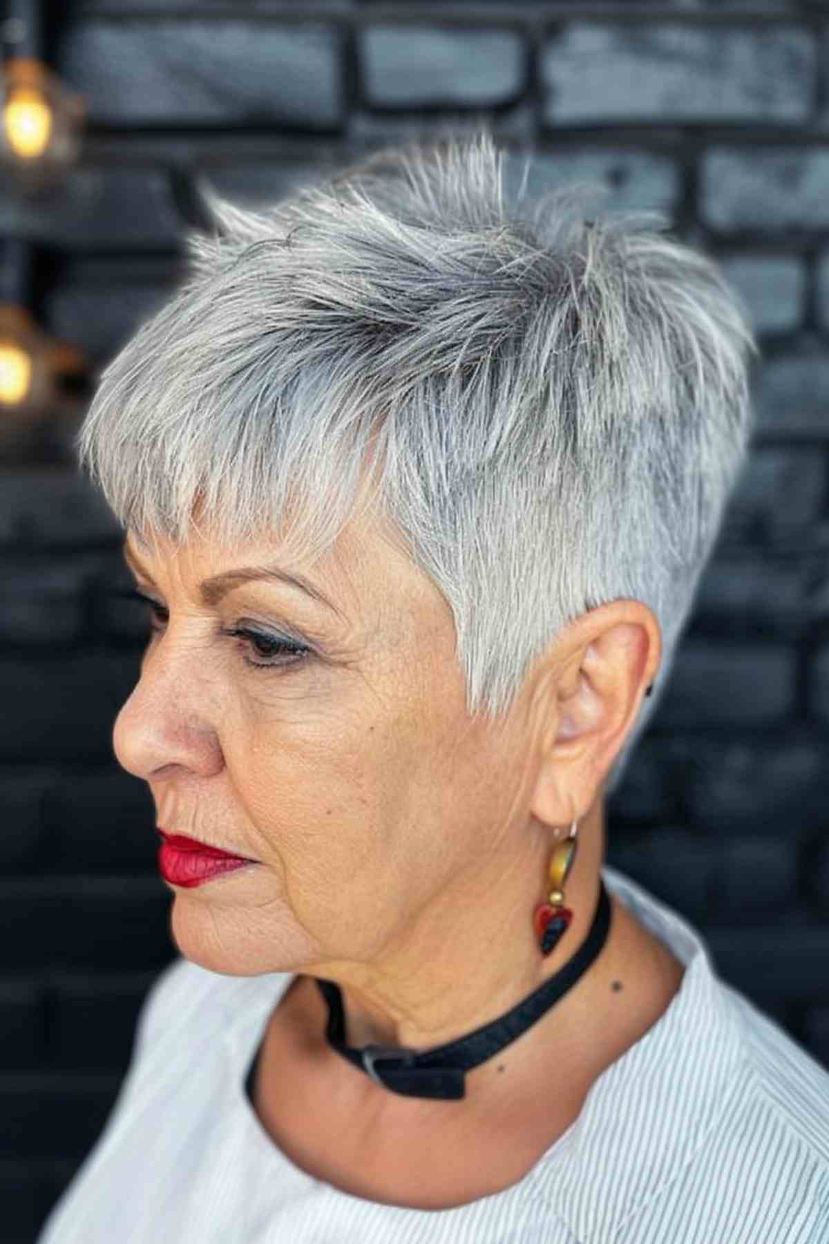 Middle-aged woman sporting a silver pixie cut with bangs and textured layers for a modern look.